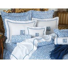 a bed with blue and white sheets and pillows