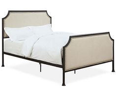 the bed is made up with white linens and black metal frame, along with pillows