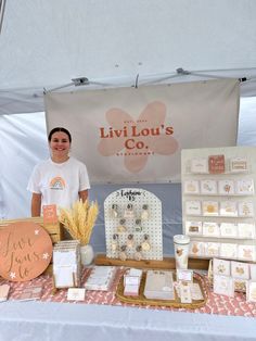 a woman standing next to a table full of items