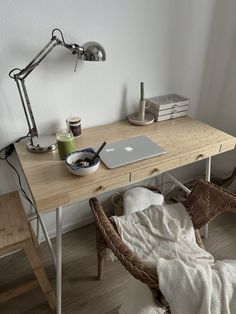 a wooden desk with a laptop computer on top of it next to a wicker chair