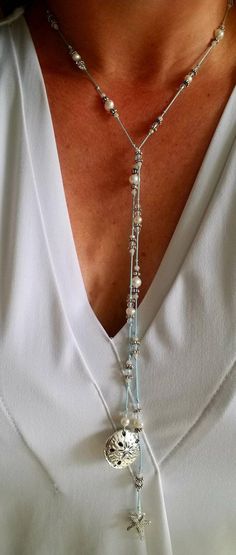 "Always bring a reminder of the ocean with you. This silk, hand knotted lariat has two beautiful focal pieces, a starfish and sand dollar. Surrounding them are crystals and fresh water pearls. The lariat is created on light blue silk. Each lariat is created upon order. There may be slight variations in the beads. This lariat does not have a clasp. Simply criss cross and flip one end over to make a Y and complete the necklace. Once worn, lariats look beautiful and do not tangle. You can accomplis Elegant Lariat Necklaces Hand Knotted, Elegant Hand Knotted Lariat Jewelry, Elegant Hand-knotted Lariat Necklaces, Bohemian Lariat Necklace As Gift, Handmade Lariat Festival Necklace, Handmade Festival Lariat Necklace, Adjustable Single Strand Lariat Necklace As Gift, Adjustable Multi-strand Lariat Necklace For Party, Unique Lariat Long Necklace Gift