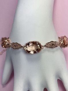 Simulated Peach Topaz Rose Gold plated Sterling Silver Bracelet Edward Design#B70 This filigree Edwardian reproduction bracelet is set with stunning oval simulated peach topaz gemstones surrounded by intricate sterling settings that alternate with lacy delicate links, all rose gold "embraced." It's adjustable chain link is closed by a lobster claw clasp. The gemstones are approximately 15 carat weight (3 stones, 5 carats each). The oval gemstones are 14mm X 10mm. The bracelet is 8.5" long at max Edwardian Jewelry, Matching Rings, Engraved Items, Topaz Gemstone, Gold Plated Sterling Silver, Sterling Silver Bracelets, Rose Gold Plates, Jewelry Sales, Topaz