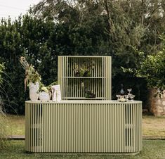 an outdoor bar made out of metal bars with plants on top and vases in the back