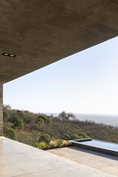 an outdoor swimming pool is seen from the inside of a house with large concrete walls and floor to ceiling windows