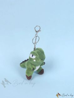 a small green stuffed animal keychain with eyes