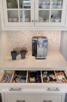 a coffee maker and some cups in a cabinet