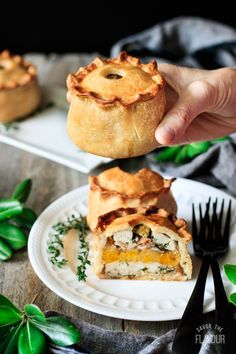 a person is holding a piece of pie on a white plate with green leaves around it