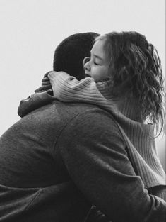 a black and white photo of a woman hugging a man's head with his arms around her