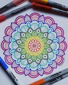 a coloring book with markers and crayons on the table next to it is an image of a colorful flower