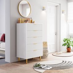 a white dresser sitting in a living room next to a mirror and potted plant