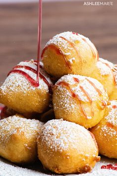 a pile of donuts sitting on top of a white plate covered in powdered sugar