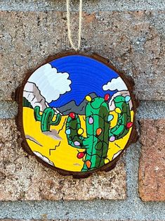 a cactus painted on the side of a brick wall hanging from a rope with string