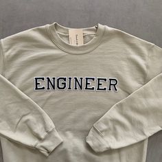 This very comfy and empowering Engineer sweatshirt is perfect for gifting to your friends and loved ones for birthdays and other celebratory events! The letters (patches) are heat pressed. Our sweatshirts run in a UNISEX fit. The sweaters naturally have a slightly oversized fit giving extra room for moving around and comfort! For this reason, we highly recommend getting your true normal size especially if you like that slight oversized fit! :) We are currently offering sizes S-L. The material is Cotton Sweatshirt With Lettering For Gift, Trendy Letter Print Sweatshirt As Gift, Crew Neck Slogan Sweatshirt As Gift, Casual Sweatshirt With Letter Embroidery As Gift, Engineer Sweatshirt, Gifts For Engineers, Engineer Graduation, Graduate Gifts, Engineer Gifts