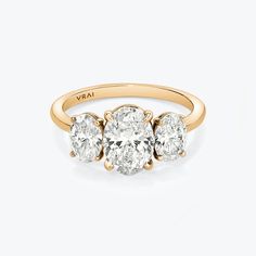 three stone diamond ring in yellow gold with diamonds on the sides and an oval shaped center