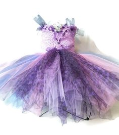 a dress made out of tulle and fabric with flowers on the bottom, sitting on top of a table