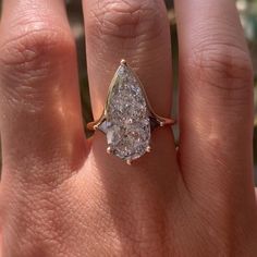 a woman's hand with a ring on it and a pear shaped diamond in the middle