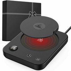 an electronic device with a red light on it and a black gift box behind it