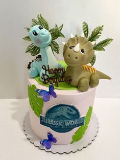 a birthday cake decorated with dinosaurs and plants