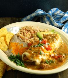 a white plate topped with mexican food next to tortilla chips