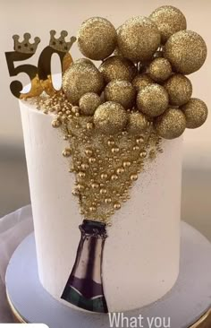 a white cake with gold decorations and a champagne bottle on top that says 50 what you want