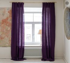 a purple curtain hanging in front of a window next to a painting on the wall