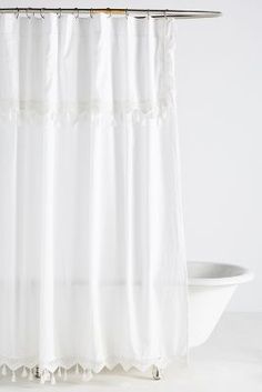 a white bath tub sitting next to a shower curtain with ruffles on it