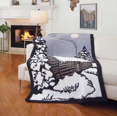 a living room with a couch, chair and fireplace covered in a blanket that has an image of a train on it