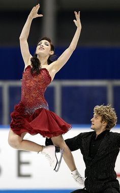 a man and woman skating on ice with one holding the other's leg in the air