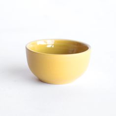 a yellow bowl sitting on top of a white table