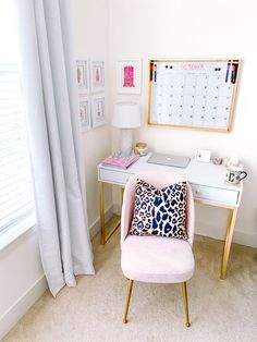 a pink chair sitting in front of a desk with a calendar on the wall behind it