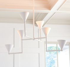 a white chandelier hanging from the ceiling in a room with windows and wooden paneling