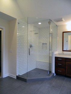 a bathroom with a walk in shower next to a sink and a mirror on the wall