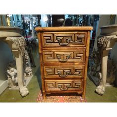 an ornate wooden chest of drawers next to statues