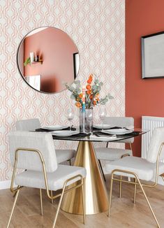 a dining room table with chairs and a round mirror on the wall above it,