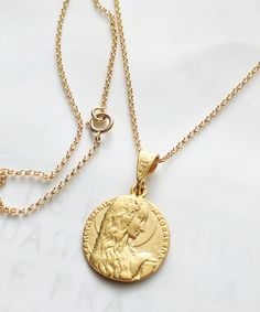 "This vintage Mary of Magdala Medal with her famous long hair captures her holding her alabaster jar. The medal is 18K gold vermeil. MAGDALA is the fishing village on the Sea of Galilee where Mary Magdalene lived before she met Jesus. The writing on the front is \"SANCTA MARIA MAGDALENA.\" The medal measures 18mm in diameter and is complete with an 18K gold vermeil bail. The chain is also 18K gold vermeil and measures 24 inches long. ALABASTER JAR OF ANOINTING OIL - Mary Magdalene anointed Jesus Alabaster Jar, The Sea Of Galilee, Gospel Of Luke, Maria Magdalena, Mary Magdalene, Ceramic Necklace, Saints Medals, Gold Wash, Fishing Villages