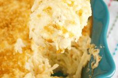 a scoopful of mashed potatoes is being lifted from a blue casserole dish