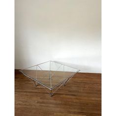 a glass table with metal legs on a wooden floor