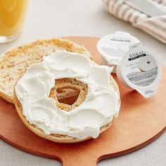 a bagel with white frosting sitting on top of a wooden plate next to a glass of orange juice