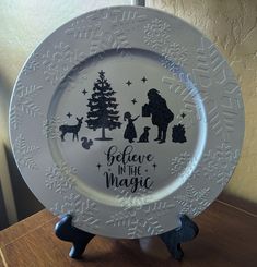 a white plate with the words believe in the magic and silhouettes of people on it