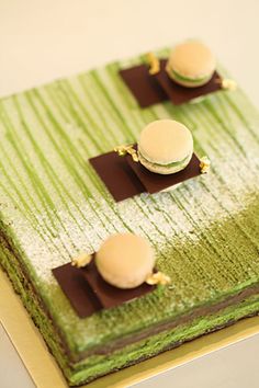 there is a green cake with three macaroons on it