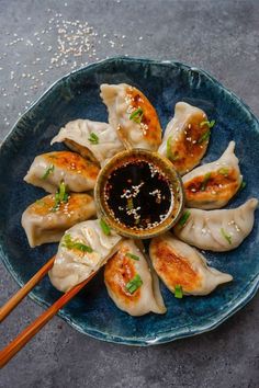 a blue plate topped with dumplings covered in sauce