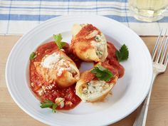 a white plate topped with stuffed shells covered in sauce and garnished with parsley