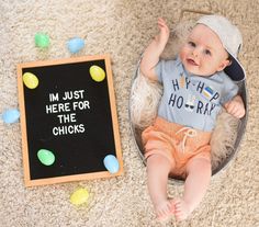 a baby is laying on the floor next to a chalkboard that says i'm just here for the chicks