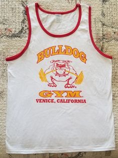 BULLDOG GYM Venice Beach California Short Sleeveless Ringer Tank Top A-shirt. Brand New without tag. Sizes Available: Medium, Large and Extra Large. 100% Cotton. Retro White Tank Top For Streetwear, Vintage Cotton Muscle Tee For Streetwear, Vintage Gym Shirt, Retro Crew Neck Tank Top With Graphic Print, Vintage Cotton Tank Muscle Tee, Venice Beach California, Bodybuilding Workout, Gym Tees, Venice California