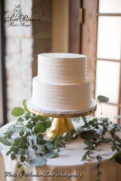 a white wedding cake with greenery on top