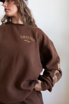 This fleece crewneck has a super cozy feel with an oversized relaxed fit and meant to be worn year-round. Espresso fleece crewneck 50% Cotton / 50% Polyester 'EMPATHY' embroidered in matching thread with raw edge espresso color appliqué across arms and back 'Empathy Always' embroidered on chest 'Mayfair' embroidered on left cuff 'it starts with you' screen printed on right wrist (Wash care instructions) Turn inside out and machine wash cold with like colors (Dry care instructions) Hang dry The Mayfair Group, Mayfair Group, Capsule Dressing, Brown Crewneck, Racing Jackets, Brown Sweatshirt, Linen Bottoms, Oversized Crewneck, White Accessories