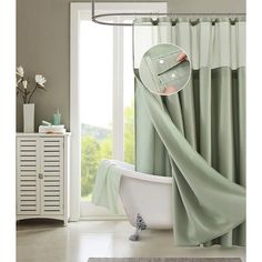 a bath tub sitting next to a window covered in a green blanket and matching shower curtain