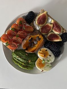 a white plate topped with sliced up fruit and veggies next to an egg