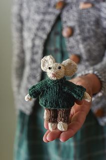 a person holding a small stuffed animal in their hand and wearing a green sweater with buttons on it