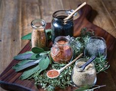 various spices and herbs on a cutting board with spoons, salt and pepper shakers